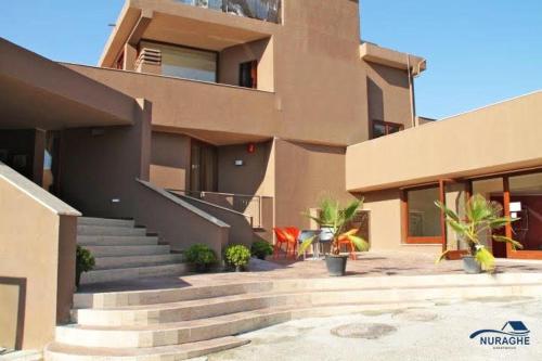 a building with stairs in front of a house at Nuraghe Apartments in Teulada