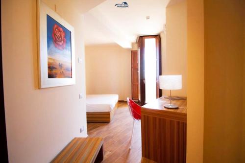 a room with a bed and a desk with a red chair at Nuraghe Apartments in Teulada