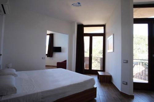 a bedroom with a white bed and a balcony at Nuraghe Apartments in Teulada
