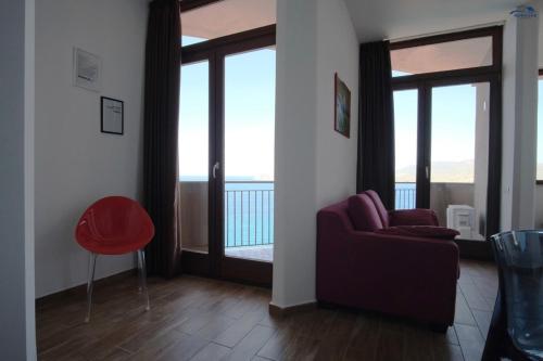 a living room with a red chair and sliding glass doors at Nuraghe Apartments in Teulada