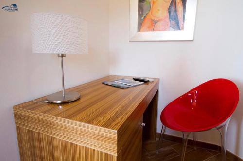 a desk with a lamp and a red chair at Nuraghe Apartments in Teulada