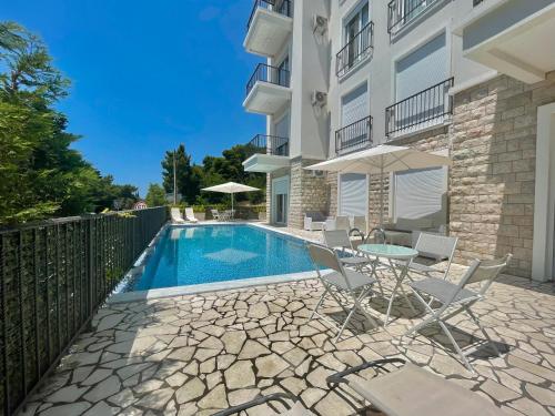 a swimming pool with a table and chairs next to a building at Seaside Apartments Sword in Bar