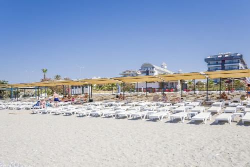 a bunch of chairs on a beach with a building at GRAND KOLİBRİ PRESTİGE in Konaklı