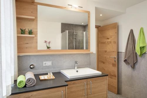 uma casa de banho com um lavatório e um espelho em daHoam Appartamenti em Rasùn di Sotto