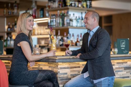 a man and a woman sitting at a bar at Hotel Schütterhof in Schladming