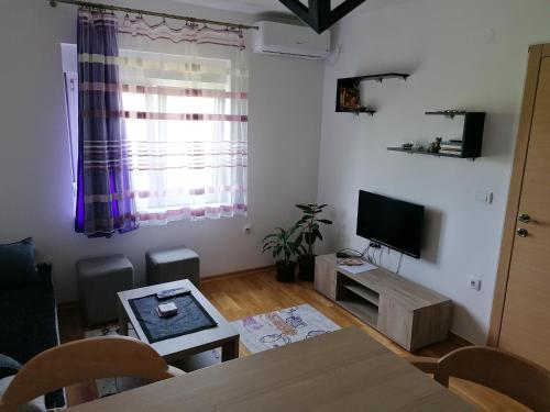 a living room with a table and a television at Apartman San in Vrnjačka Banja