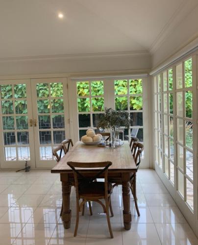 a dining room with a table and chairs and windows at Howlong Old Post Office Luxury Suite in Howlong