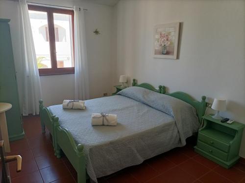 a bedroom with a green bed with two towels on it at Ca' margo in Calasetta