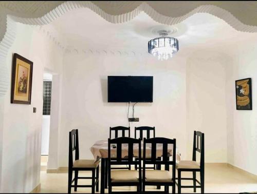 a dining room with a table and chairs and a tv at Appartement Charmant in Fnidek