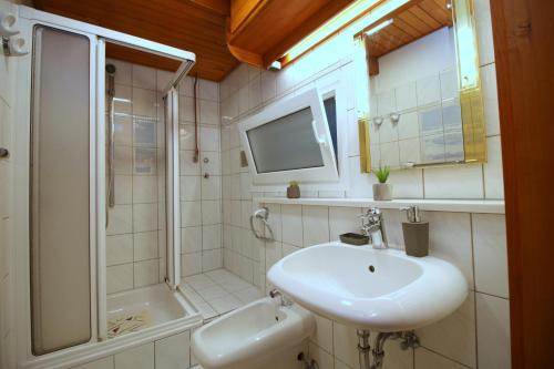 une salle de bain blanche avec un lavabo et une douche dans l'établissement Villa Monterose, à Malija