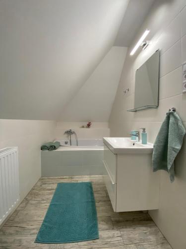 a white bathroom with a sink and a bath tub at Oázis apartmanház in Fertőszentmiklós