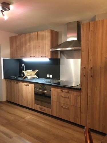 une cuisine avec des armoires en bois et un four à plaques de cuisson dans l'établissement La Villa de Claire, à Gréoux-les-Bains