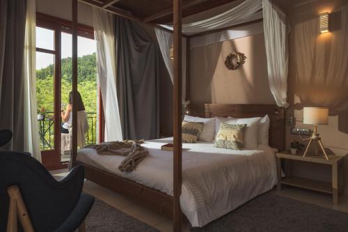a bedroom with a canopy bed and a woman standing outside at Rouista Tzoumerka Resort in Vourgareli