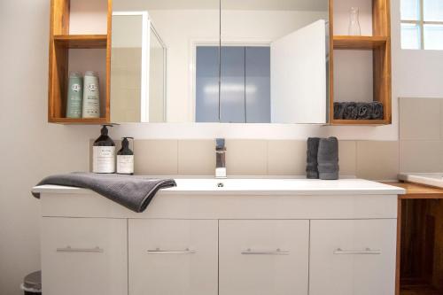 a bathroom with a white sink and a mirror at Cottesloe Beach View Apartments #7 in Perth