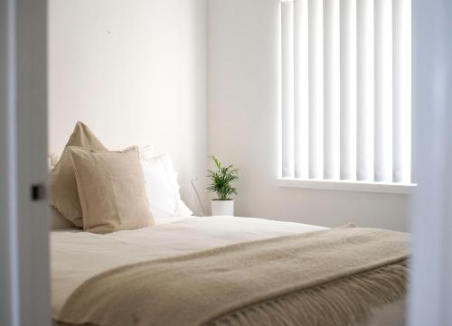 a bedroom with a bed with white walls and a window at Cottesloe Beach View Apartments #7 in Perth