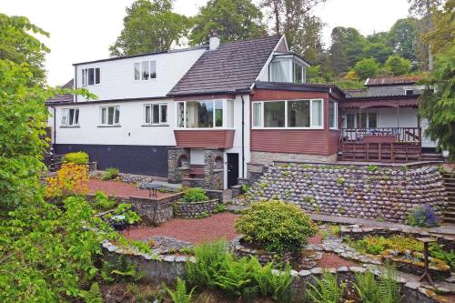 a house with a stone wall and a yard at Elderslie Guest House in Oban