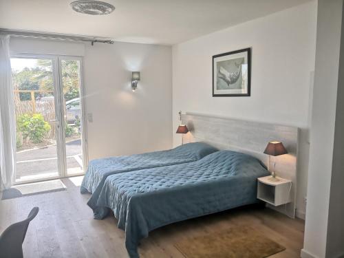 a bedroom with a bed with a blue comforter and a window at Hotel L'Ancre d'or in Pénestin