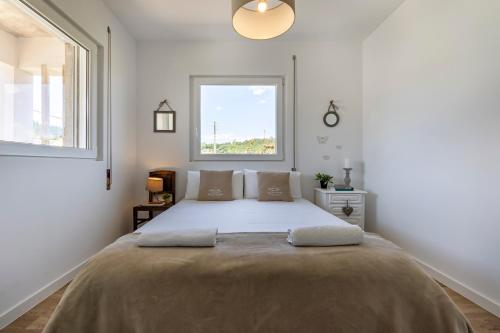 a white bedroom with a large bed with a window at Charming Country House in Ourém