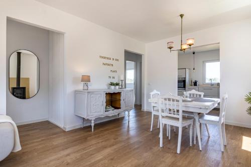 a white dining room with a table and a mirror at Charming Country House in Ourém