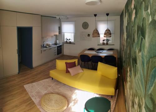 a living room with a yellow couch and a kitchen at Rainbow apartment, Koper in Koper
