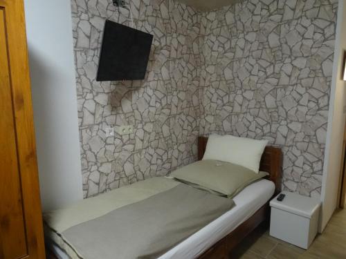 ein kleines Bett in einem Zimmer mit einer Steinmauer in der Unterkunft Pension und Gästehaus Paffrath in Großbrembach