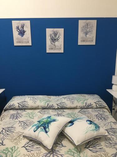 a bedroom with a bed with a blue wall with pictures at CASA WELA OLBIA in Olbia