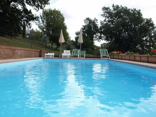 a large blue swimming pool with chairs and umbrellas at Agriturismo Podere 3 Querce in Manciano