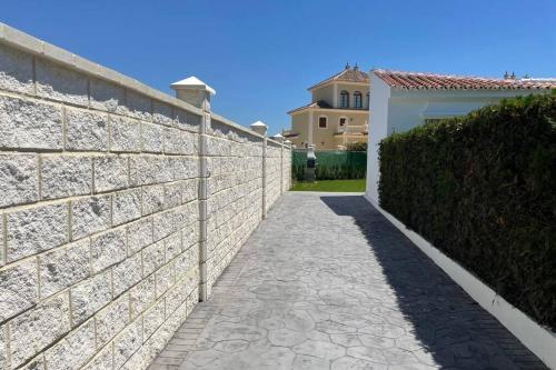 a stone retaining wall with a sidewalk next to a building at La Juli, Exclusivo chalet nuevo, de lujo in Matalascañas