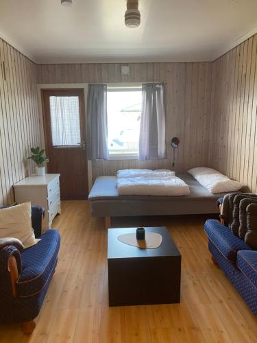 a room with a bed and two chairs and a table at Solvang Ferietun in Vangsnes