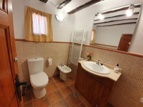 un bagno con un water, un lavandino e uno specchio di Casa Rural del Pantano 4 Estrellas a Buenache de Alarcón