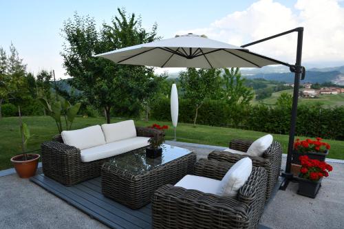 a patio with wicker chairs and a table with an umbrella at B&B Bricco della Guardia in Briaglia