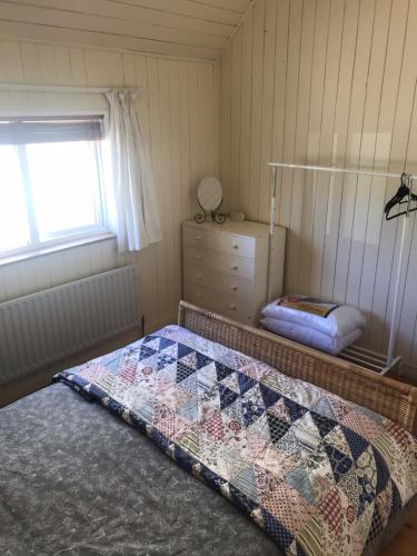 a bedroom with a bed and a dresser and a window at Mo's Cottage in Kilmore
