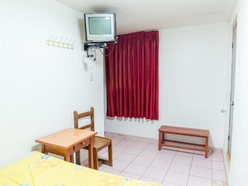 Habitación con mesa y TV en la pared. en Hostal Ñaña, en Huaraz