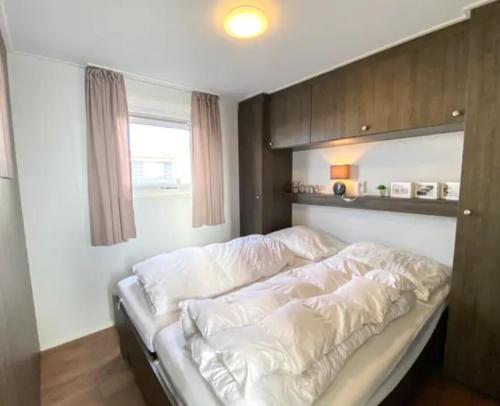 Chalet Oceanside Zeeland في سيروسكيرك: سرير أبيض في غرفة بها نافذة