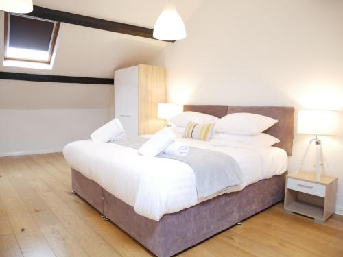 Nordic Suites Apartment, Ulverston في أولفيرستون: غرفة نوم بسرير كبير عليها شراشف ووسائد بيضاء