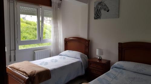 Un dormitorio con 2 camas y una ventana con una foto de cebra. en Apartamento Julieta, en San Vicente de la Barquera