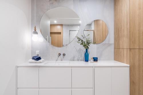 a white bathroom with a sink and a mirror at Blue16 by OneApartments in Gdańsk