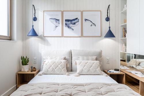 a bedroom with a bed with four pictures on the wall at Blue16 by OneApartments in Gdańsk