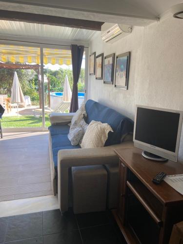 een woonkamer met een blauwe bank en een televisie bij Quintinha do Zé da Lola in Silveiras