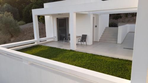 a white house with a patio and grass at Studio Vasileios-The Best Luxury Guest Room in Spili in Spílion