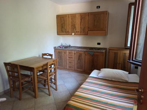 a kitchen with a table and wooden cabinets and a bed at Agriturismo Macìn in Cesena