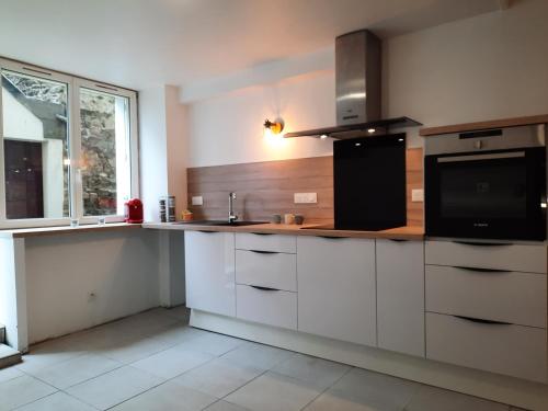a kitchen with white cabinets and a black appliance at Granville plage normandie mont saint Michel in Granville