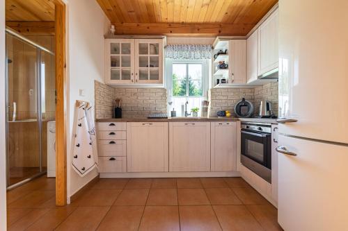 a kitchen with white cabinets and a wooden ceiling at CHALUPA NA VYHLÍDCE in Jeseník
