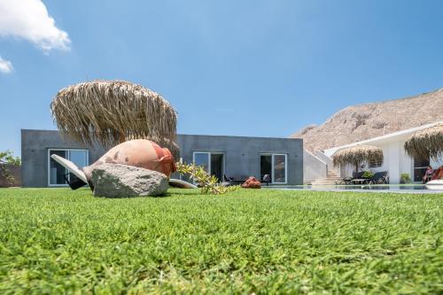 a house with a sculpture in the grass at Sagma Villas in Perissa