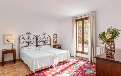 a bedroom with a white bed and a red rug at Finca Son Blat in Porto Cristo