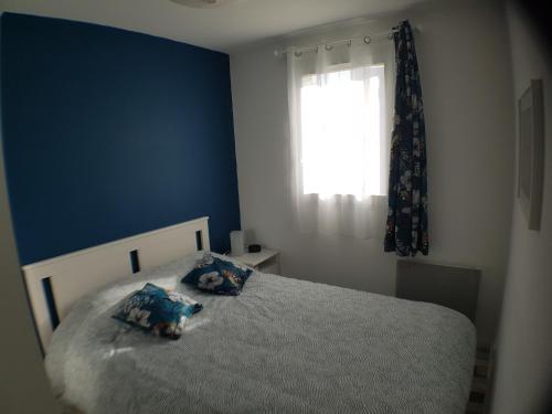 une chambre avec un lit aux murs bleus et une fenêtre dans l'établissement Le COCON CABOURGEAIS, à Cabourg