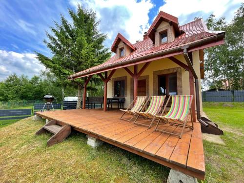 a house with two chairs on a wooden deck at Domek nad jeziorem w Leleszkach in Leleszki