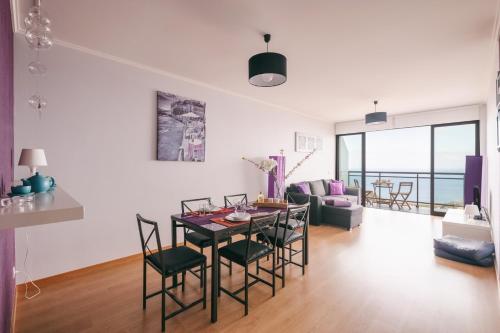 a dining room and living room with a table and chairs at Reed´s View in Caniço