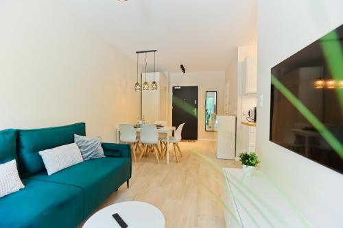 a living room with a blue couch and a kitchen at M&K Apartament Nadmorski Zagajnik - Sobieszewo, Wyspa Sobieszewska in Gdańsk