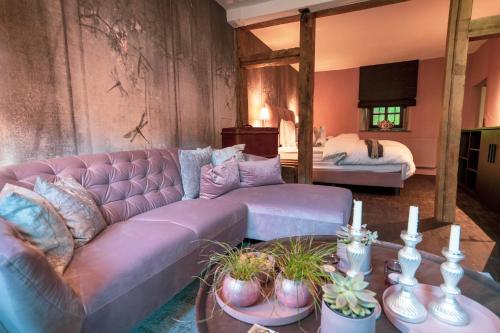 sala de estar con sofá púrpura y cama en LÖFFELMÜHLE BOUTIQUE BED AND BREAKFAST, en Pillig